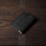 Black leather passport case on a wooden surface