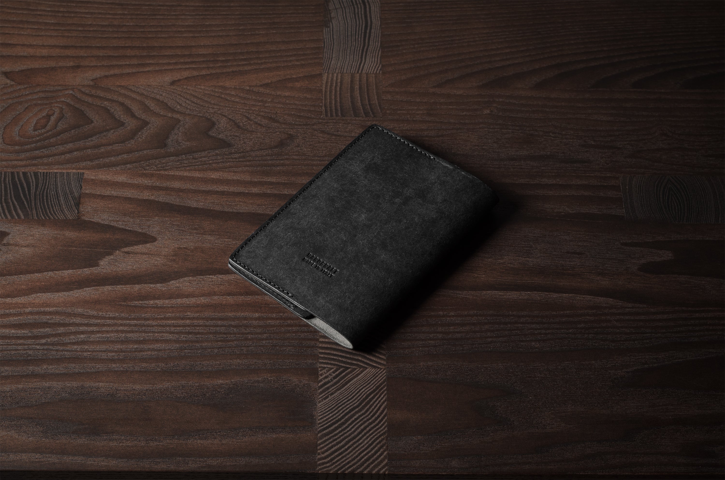 Black leather passport case on a wooden surface