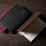 Black and brown leather passport cases on a wooden surface