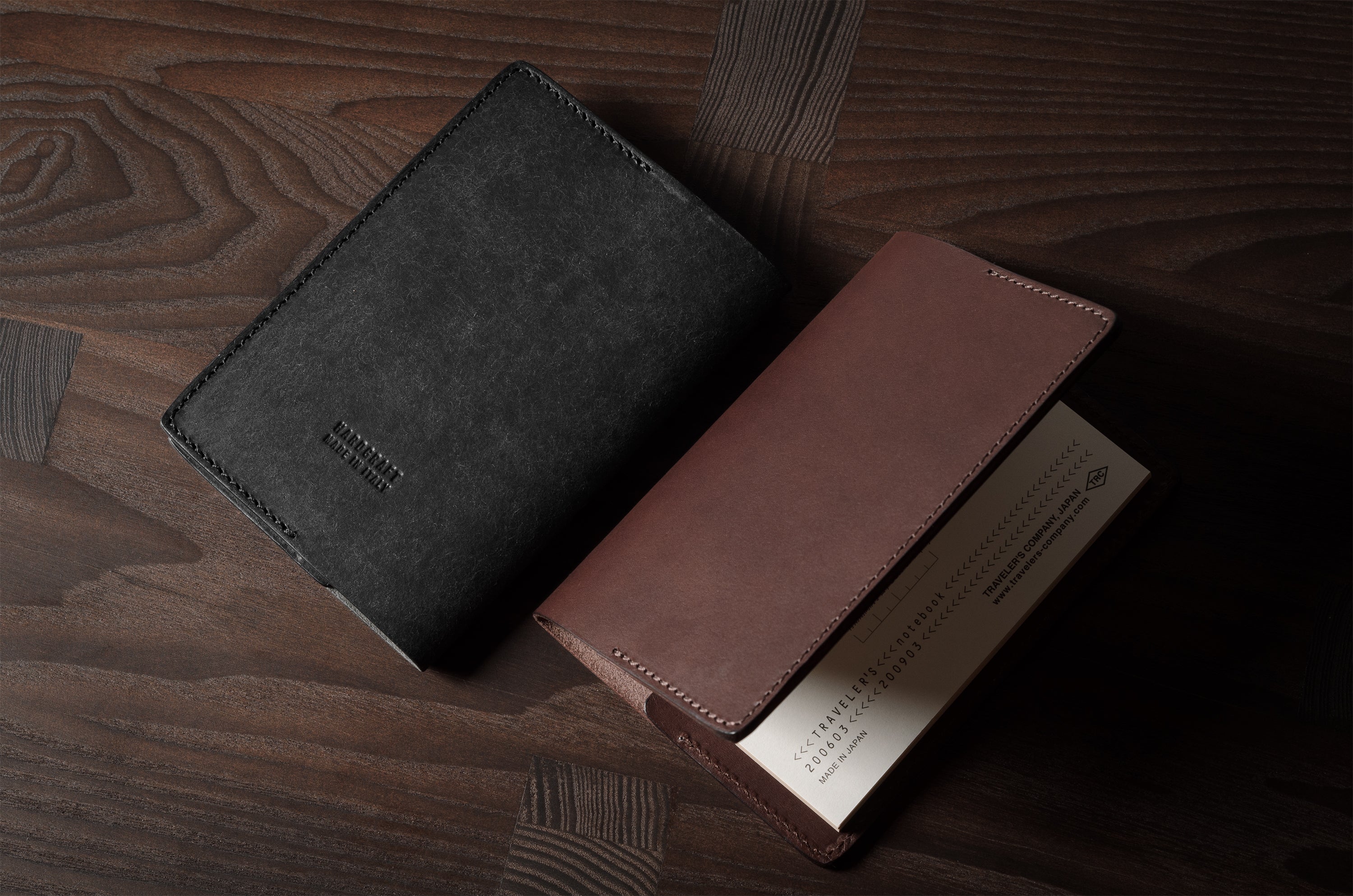 Two leather passport wallets, one black and one brown, on a wooden surface.