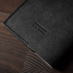 Black leather passport case on a wooden surface