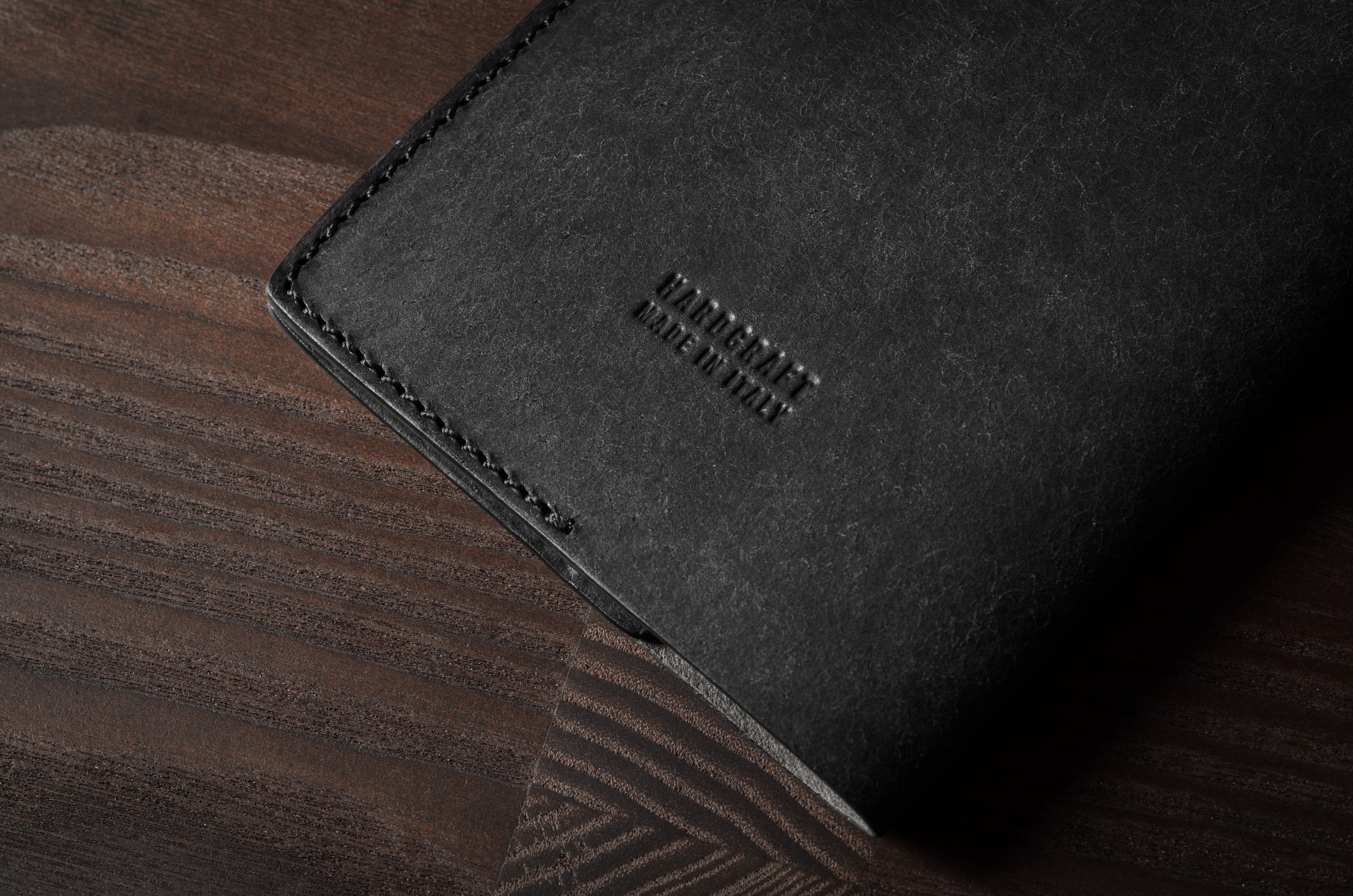 Black leather passport case on a wooden surface