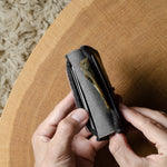 Person holding a compact wallet on a wooden surface with a textured background