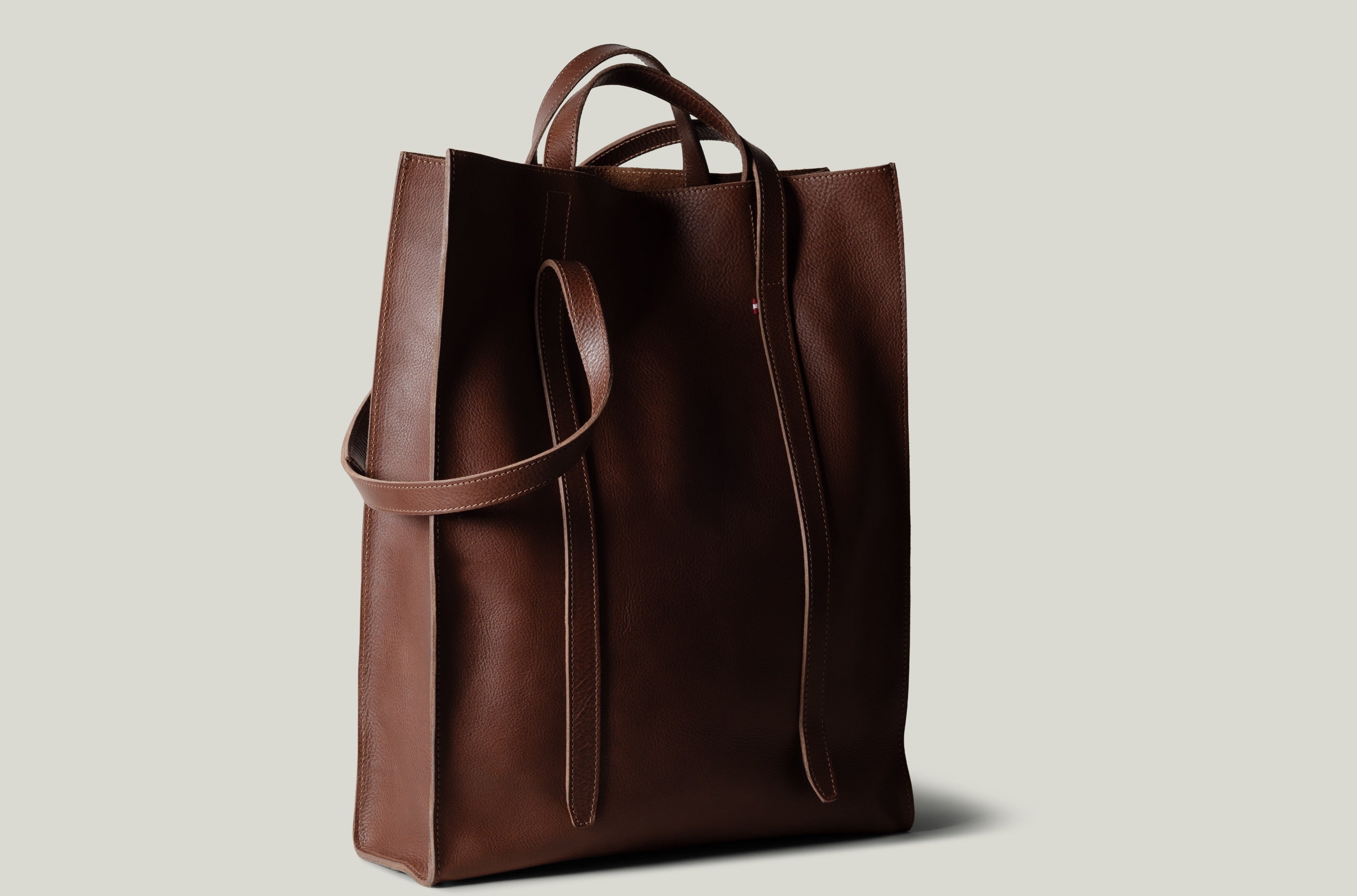 Brown leather tote bag on a light gray background