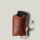 Brown leather key pouch with a black object inside on a light gray background