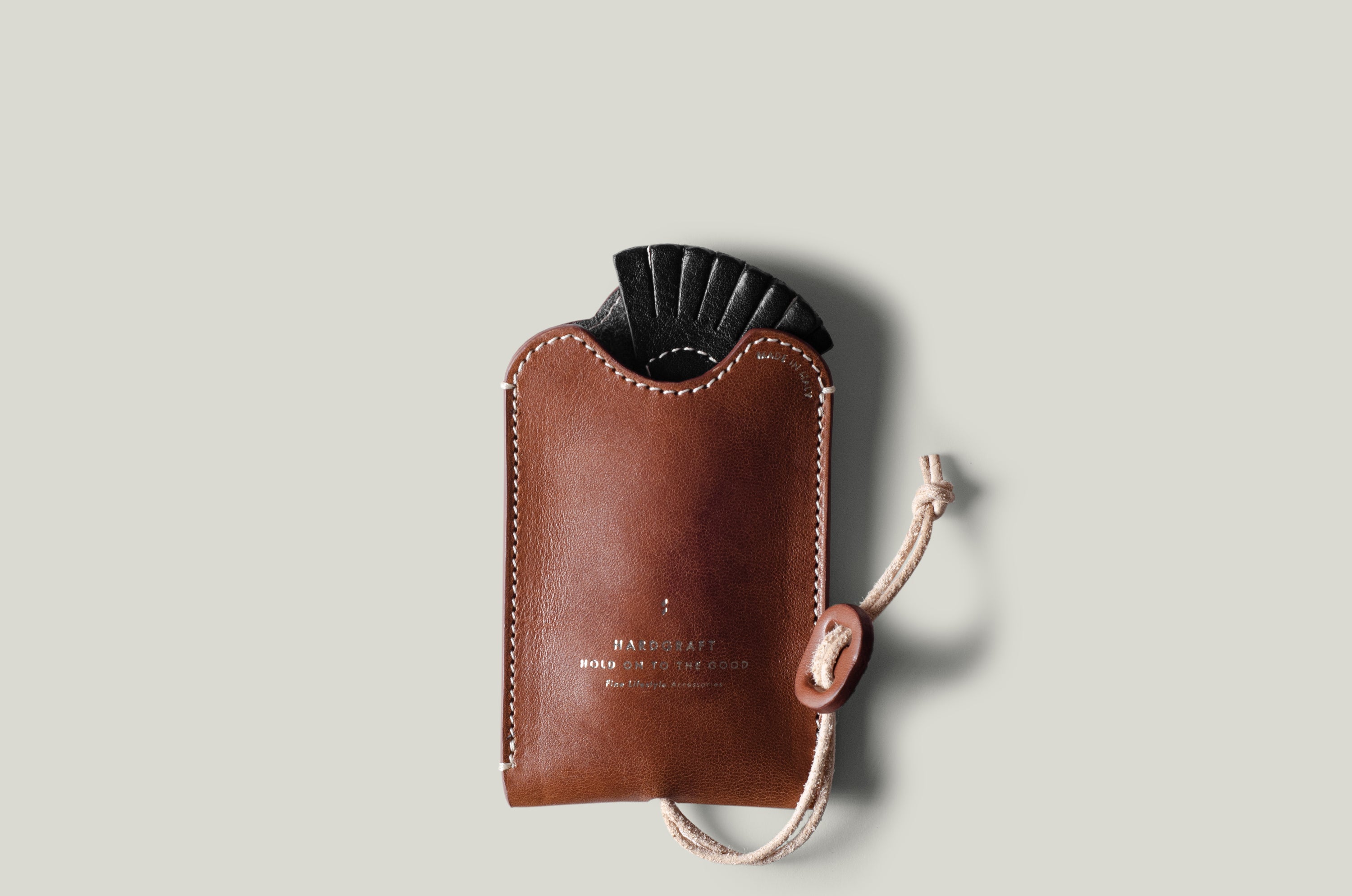 Brown leather key pouch with a black object inside on a light gray background