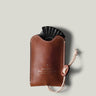 Brown leather key pouch with a black object inside on a light gray background