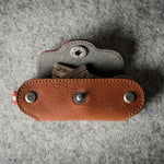 Multi-key pouch made of brown leather on a gray background
