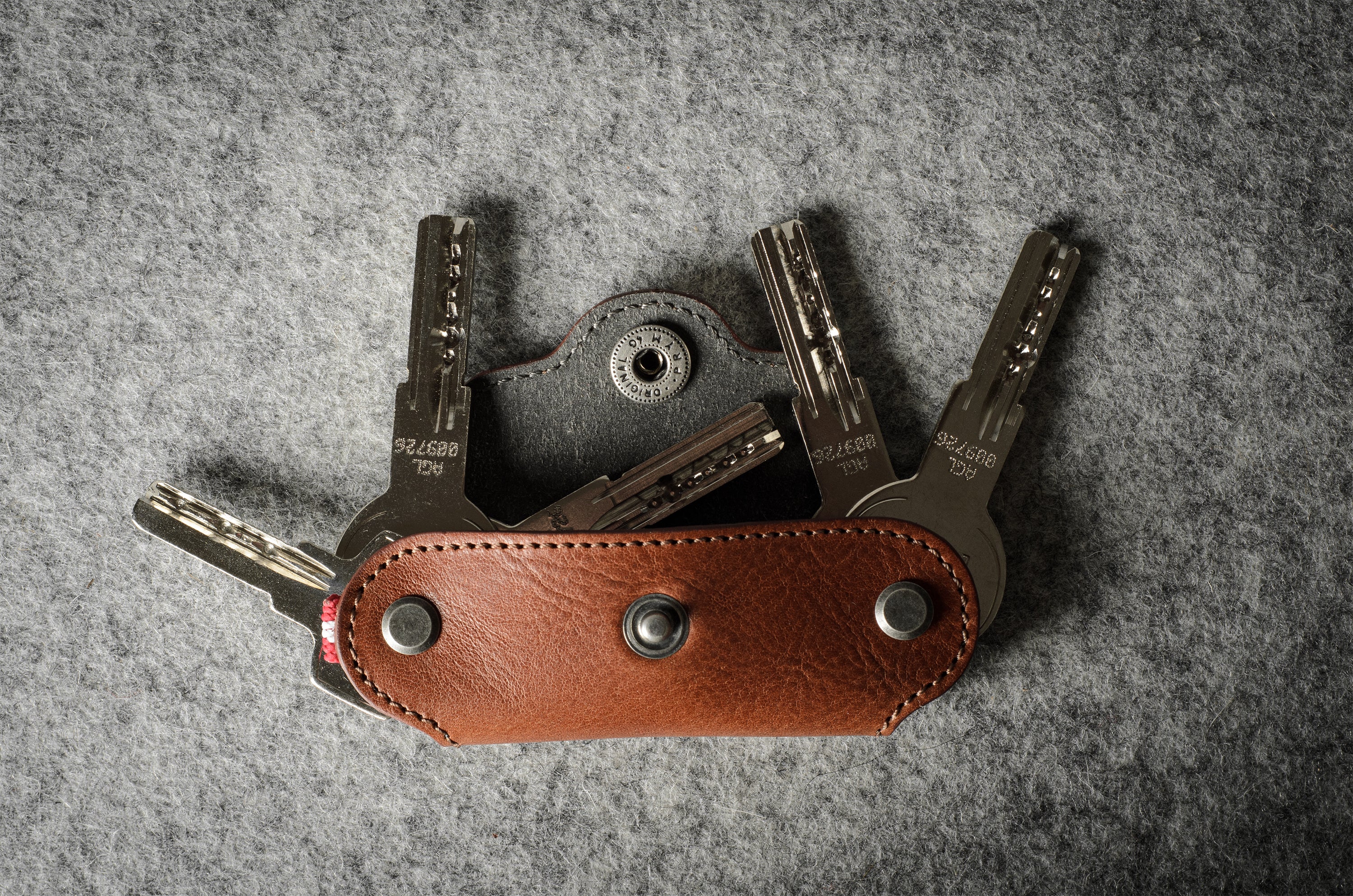 Multi-key pouch made of brown leather on a gray background