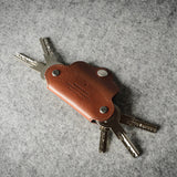 Multi-key pouch made of brown leather on a gray background