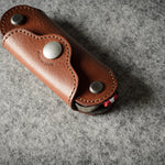 Multi-key pouch made of brown leather on a gray background