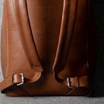 Brown leather backpack on a gray background