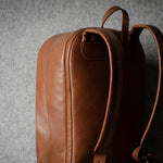 Brown leather backpack on a gray background
