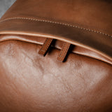 Close-up of a brown leather backpack with visible stitching