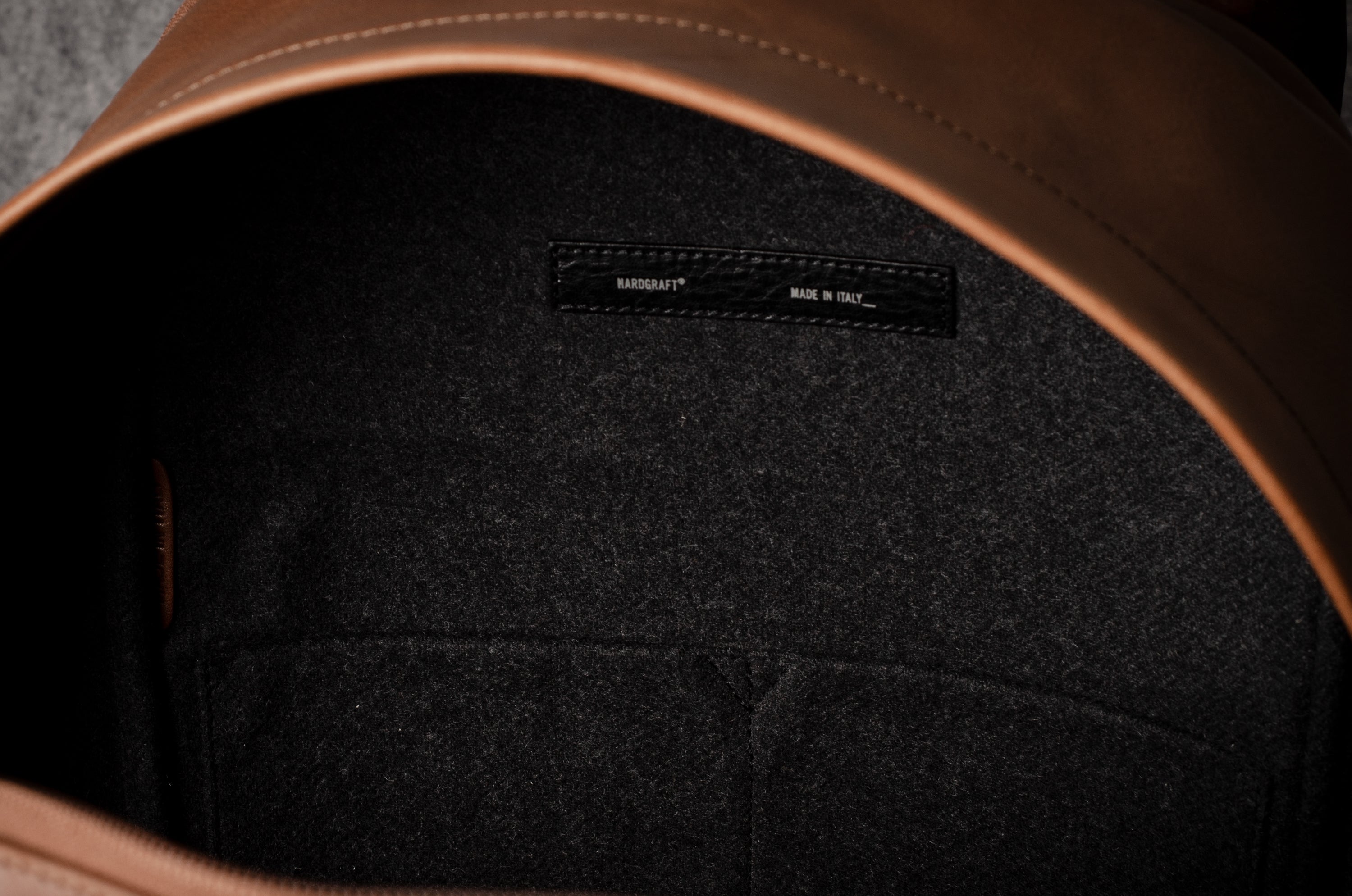Close-up of a leather backpack with a hardgraft label on a dark background