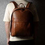 Person wearing a brown leather backpack against a dark background