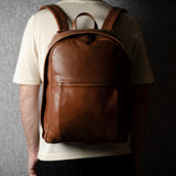 Person wearing a brown leather backpack against a dark background
