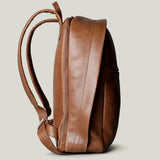 A brown full leather backpack with two adjustable leather shoulder straps and a zippered closure.